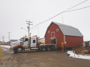 Workers lift the power lines along Railway Avenue as a semi hauling a 1947 barn makes its way to the Spruce Grove Ag Society on March 3. - Photo by Marcia Love