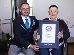 In this photo supplied by the Guinness World Records, Marco Frigatti, Head of Records for Guinness World Records, left, presents Israel Kristal with a certificate for being the oldest living man, in Haifa, Israel, Friday, March 11, 2016. Guinness said in a statement that Kristal is 112 years and 178 days old as of March 11. (Dvir Rosen/Guinness World Records via AP)