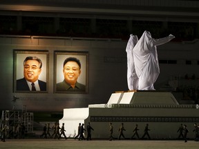 Large covered statues of North Korea's founder Kim Il-sung and former leader Kim Jong-il are wheeled past their portraits after the parade celebrating the 70th anniversary of the founding of the ruling Workers' Party of Korea, in Pyongyang October 10, 2015. Isolated North Korea marked the 70th anniversary of its ruling Workers' Party on Saturday with a massive military parade overseen by leader Kim Jong Un, who said his country was ready to fight any war waged by the United States.  REUTERS/Damir Sagolj