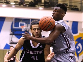 Carleton’s Kaza Kajami-Keane and Caleb Agada of Ottawa have the basketball bounce awkwardly off both of them during an OUA semifinal at the Mattamy Athletic Centre. (Craig Robertson, Postmedia Network)