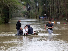 Zavion Watson, right, pulls a boat full of relatives to dry land Friday, March 11, 2016, as they evacuate their homes on West Fontana Road in Independence, La., after heavy rains caused low areas to flood. (AP Photo/Scott Threlkeld)