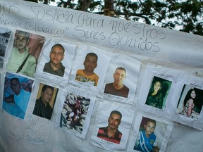 A banner with photos of several missing miners hangs on a tree near Tumeremo, Venezuela, Tuesday, March 8, 2016. Demonstrators are blocking the main road that connects Venezuela and Brazil in protest against the disappearance of 28 miners. (Fabiola Ferrero/El Estimulo via AP)
