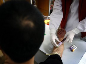 A man has a sample of blood taken by a nurse for testing at the HIV/AIDS ward of Beijing YouAn Hospital December 1, 2011. (REUTERS/David Gray)