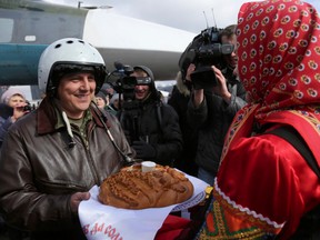 In this photo provided by the Russian Defense Ministry Press Service, a Russian pilot who returned from Syria is welcomed with traditional bread-and-salt at an airbase near the Russian city Voronezh on Tuesday, March 15, 2016. Russian warplanes and troops stationed at Russia's air base in Syria started leaving for home on Tuesday. (Russian Defense Ministry Press Service via AP)