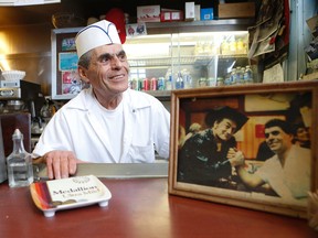 Jimmy Tsirimokos with a photo of himself and Stompin' Tom Connors - who came in to eat after shooting the video for Margo's Cargo - at his Olympos Crow-Bar Restaurant diner on Princess St. Monday, March 14, 2016. (Jack Boland/Toronto Sun)