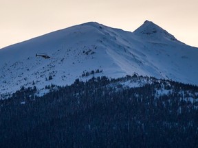 A helicopter flies past a snow-capped mountain top near McBride, B.C., on Saturday January 30, 2016. THE CANADIAN PRESS/Darryl Dyck