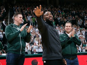 Former Michigan State player Mateen Cleaves, center, waves as he is introduced with Michigan State's 2000 national championship team during halftime of Michigan State-Florida NCAA college basketball game, Saturday, Dec. 12, 2015, in East Lansing, Mich. Also seen are Jason Andreas, left, and Mat Ishbia, right. (AP Photo/Al Goldis)