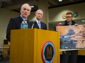 An aide to Metro General Manager Paul Wiedefeld, left, holds up a photo of a track damaged by fire as Wiedefeld speaks during a news conference to announce that the DC Metrorail service will be shut down for a full day, at the Washington Metropolitan Area Transit Authority headquarters, on Tuesday, March 15, 2016, in Washington. (AP Photo/Evan Vucci)