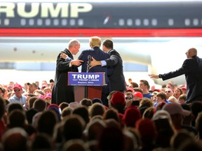 Security personnel surround Republican presidential candidate Donald Trump after a man tried to rush the stage during a campaign rally in Vandalia, Ohio, outside of Dayton, on Saturday, March 12, 2016. The man was stopped and Trump continued with his speech. (Carrie Cochran/The Cincinnati Enquirer via AP)
