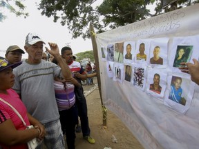People look at displayed pictures of missing miners in Tumeremo in Bolivar state, Venezuela March 7, 2016. REUTERS/Stringer FOR