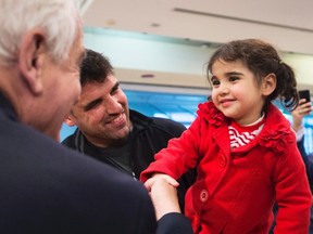 John McCallum, left, Minister of Immigration, Refugees and Citizenship, meets two-year-old Syrian refugee Minisa, right, and her father Yousef, centre, at Pearson International Airport in Toronto on Monday, February 29, 2016. THE CANADIAN PRESS/Nathan Denette