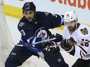 Winnipeg Jets defenceman Dustin Byfuglien (left) battles with Chicago Blackhawks forward Andrew Ladd in Winnipeg on Fri., March 18, 2016. Kevin King/Winnipeg Sun/Postmedia Network