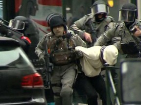 In this framegrab taken from VTM, armed police officers escort Salah Abdeslam to a police vehicle during a raid in the Molenbeek neighborhood of Brussels, Belgium, Friday March 18, 2016. The identity of Salah Abdeslam is confirmed Saturday March 19, 2016, by French police and deputy mayor of Molenbeek, Ahmed El Khannouss quoting official Belgium police sources. After an intense four-month manhunt across Europe and beyond, police on Friday captured Salah Abdeslam, the top suspect in last year's deadly Paris attacks, in the same Brussels neighborhood where he grew up.  (VTM via AP)