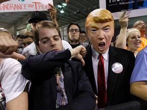 A supporter for Democratic presidential candidate Sen. Bernie Sanders, I-Vt., gives the thumbs down sign to a fellow Sanders' supporter wearing a Donald Trump mask during a campaign rally, Saturday, March 19, 2016 in Phoenix. (AP Photo/Ralph Freso)