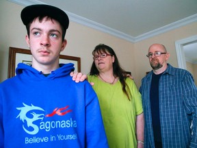 CLIFFORD SKARSTEDT/postmedia network
Justin Bullock, 13, reflects next to his father Grant and his stepmother Becky Smith at his grandparents home last Thursday. Justin is a special needs students attending the Sagonaska Demonstration School in Belleville. Sagonaska and four other schools for special needs students might be closing their doors.