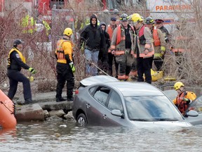 Emergency crews work to remove a vehicle from the Credit River after it went through a fence on Monday, March 21, 2016. (Andrew Collins/Postmedia Network)