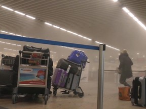In this photo provided by Ralph Usbeck, an unidentified traveller runs in a smoke-filled terminal at Brussels Airport, in Brussels after explosions on March 22, 2016. (Ralph Usbeck via AP)