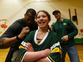 Mikaela Arroyo, 10, gets an autograph from Edmonton Eskimos D'Anthony Batiste (left) and Grant Shaw after they spoke to students at Sweet Grass Elementary School about bullying on Tuesday. (Ian Kucerak)