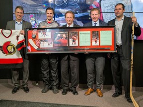 From left to right, Laurie Boschman, Erik Karlsson, Eugene Melnyk, Daniel Alfredsson and Chris Phillips hold some pieces of Senators history at a news conference yesterday. (Wayne Cuddington/Postmedia Network)