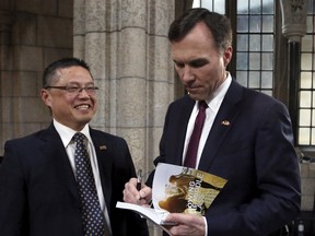 Canada's Finance Minister Bill Morneau signs a copy of the budget for Raymond Louie, president of the Federation of Canadian Municipalities, after delivering the budget on Parliament Hill in Ottawa March 22, 2016. REUTERS/Patrick Doyle