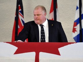 Then-mayor Rob Ford places his hand on the coffin of Jack Layton, then-leader of the federal New Democratic Party (NDP) party, inside City Hall in Toronto on August 25, 2011. REUTERS/Mike Cassese