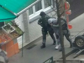 In this Friday, March 18, 2016 photo made available Monday March 21, an unidentified man believed to be connected to key suspect in the November 2015 Paris attacks Salah Abdeslam, is detained by police during a raid in the Molenbeek neighborhood of Brussels, Belgium. Abdeslam was arrested Friday March 18, in Molenbeek after a four-month manhunt, and investigators are known to be still hunting for other suspects on their wanted list.(AP Photo/Zouheir Ambar)