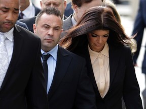 In this Oct. 2, 2014, file photo, "The Real Housewives of New Jersey" stars Giuseppe "Joe" Giudice, center, and his wife, Teresa Giudice. (AP Photo/Julio Cortez, File)