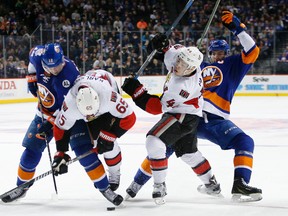 New York Islanders left winger Josh Bailey fends off Ottawa Senators defenceman Erik Karlsson as New York Islanders centre John Tavares and Ottawa Senators centre Jean-Gabriel Pageau battle during second-period NHL action in New York on March 23, 2016. (AP Photo/Kathy Willens)