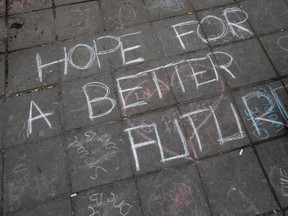 A woman writes a text on the pavement as people gathered to observe a minute of silence and mourn for the victims of the bombings at the Place de la Bourse in the center of Brussels, Belgium, on Thursday, March 24, 2016.