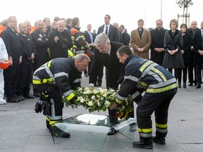 Belgium's King Philippe, centre, and firefighters lay a wreath in front of the damaged Zaventem Airport terminal in Brussels on Wednesday, March 23, 2016. The DH newspaper reports the suicide bombers were originally considering an attack on a nuclear site in Belgium, but arrests started last week may have forced them to switch to targets. (AP Photo/Frederic Sierakowski, Pool)