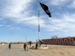 Iraqi security forces work on lowering the Islamic State flag, west of Ramadi, March 9, 2016. Picture taken March 9, 2016. (REUTERS/Stringer)