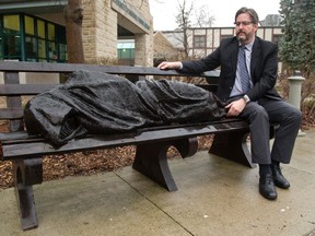 David Sylvester, principal of King?s University College in London, sits next to the sculpture of Homeless Jesus on campus. The sculpture continues to turn heads. (MIKE HENSEN, The London Free Press)