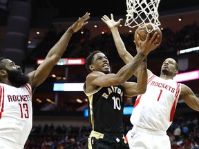 Toronto Raptors' DeMar DeRozan goes up for a shot as Houston Rockets' Trevor Ariza and James Harden defend during the first quarter of an NBA basketball game Friday, March 25, 2016, in Houston. (AP Photo/David J. Phillip)
