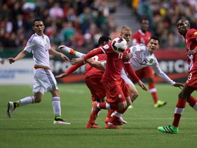 Canada's Marcel De Jong, centre, and Mexico's Hirving Lozano, centre right, vie for the ball during first half FIFA World Cup qualifying soccer action in Vancouver, B.C., on Friday March 25, 2016. (THE CANADIAN PRESS/Darryl Dyck)
