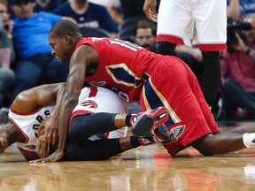 Toronto Raptors guard Kyle Lowry, on ground, fights for a loose ball with New Orleans Pelicans guard Toney Douglas in New Orleans, Saturday, March 26, 2016. (AP Photo/Gerald Herbert)