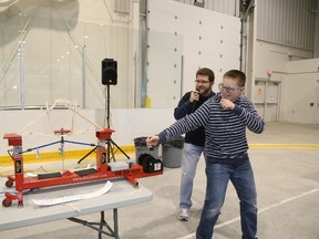 Callum Friar is cheered on by Peter Zandbergen, chair of the Quinte Chapter of Professional Engineers of Ontario,as he tests his popsicle bridge