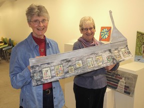 Janet Elliott, left, and Phillida Hargreaves, members of the Kingston Fibre Artists, in the community gallery at the Tett Centre. They are holding a fibre art piece depicting the centre, made by Elliott and Robin Laws Field, for a show and sale by the members of the group next month. (Michael Lea/The Whig-Standard)