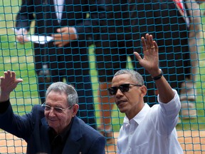 U.S. President Barack Obama, right, and his Cuban counterpart Raul Castro wave to cheering fans as they arrive for a baseball game between the Tampa Bay Rays and the Cuban national baseball team, in Havana, Cuba,  last week. (ASSOCIATED PRESS PHOTO)