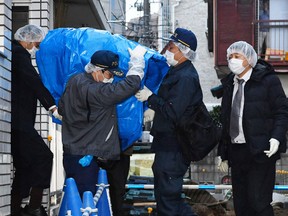 Police officers carry a sheet-covered computer from the apartment of abduction suspect Kabu Terauchi in Tokyo on March 28, 2016. Japanese police captured the 23-year-old man in an abduction case after a teenage girl escaped and ran for freedom a day earlier after being held captive in his apartment for nearly two years. (Kyodo News via AP)