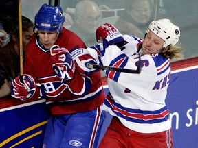 Montreal Canadiens Alex Kovalev is checked into the boards by New York Rangers Darius Kasparaitis during their first period NHL game in Montreal March 11 , 2006.