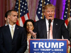 In this March 15, 2016 file photo, Donald Trump's campaign manager Corey Lewandowski listens at left as Trump speaks in Palm Beach, Fla. Florida police have charged Lewandowski with simple battery in connection with an incident earlier in the month involving a reporter. (AP Photo/Gerald Herbert, File)