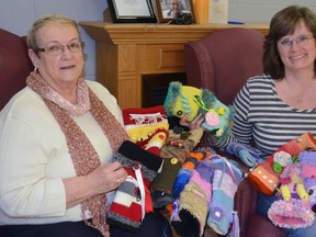 Knitters Barb Shill, left, and Deborah Peach delivered 19 handmade twiddle muffs to Caressant Care Bonnie Place Tuesday afternoon. The knit sleeves, which have many different colours, shapes and textures, give dementia patients a sensory-stimulating activity for their hands.