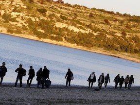 Refugees walk along a beach before trying to travel to the Greek island of Chios from the western Turkish coastal town of Cesme, in Izmir province, Turkey, in this March 5, 2016 file photo. REUTERS/Umit Bektas