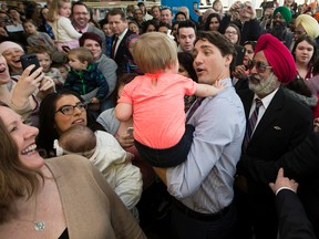 Prime Minister Justin Trudeau picks up a baby while visiting with Edmontonians during a stop at the Mill Woods branch of the Edmonton Public Library, in Edmonton Alta. on Wednesday March 30, 2016. Photo by David Bloom