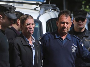 EgyptAir plane hijacking suspect Seif Eddin Mustafa, second left, is escorted by Cyprus police officers as he leaves a court after a remand hearing as authorities investigate him on charges including hijacking, illegal possession of explosives and abduction in the Cypriot coastal town of Larnaca, on March 30, 2016. (AP Photo/Petros Karadjias)