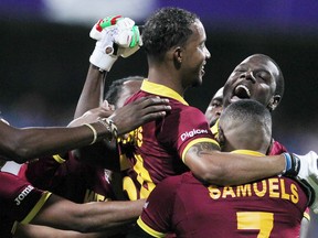 West Indies’ Lendl Simmons (middle) is held aloft by teammates as they celebrate their win over India in their semifinal match on Thursday. (AP)