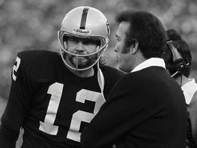 In this Dec. 10, 1979, file photo, Oakland Raiders quarterback Ken Stabler listens carefully as his coach Tom Flores discusses the situation in the last minutes of an NFL football game against the Cleveland Browns in Oakland, Calif.  (AP Photo/Robert H. Houston, File)