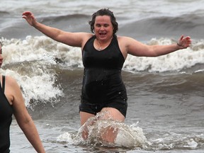 Cathy Lithgow moves through Lake Huron on her way back to the Ipperwash Beach shore after a polar bear dip there Friday. The Warwick Township woman was raising money to help her husband Steve recover from a brain injury. (Tyler Kula, The Observer)