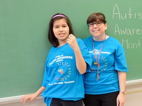 Jay-lyn, left, stands alongside educational assistant Jessica McCallum, right, in a classroom at Walpole Island Elementary School. Jay-Lyn is one of five students with autism at the school, and helped design the logo on WIES's new Autism Awareness shirts. Photo taken April 1 at Walpole Island, ON. (Louis Pin, Postmedia Network)