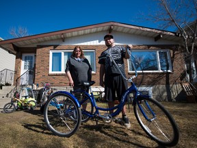 Kris Lawrence, right, and his mother Julie pose for a portrait at their Canora home in Edmonton, Alta., on Friday, April 1, 2016. Lawrence's bike was a costly purchase and will now cost more for further repair. (Ryan Wellicome)